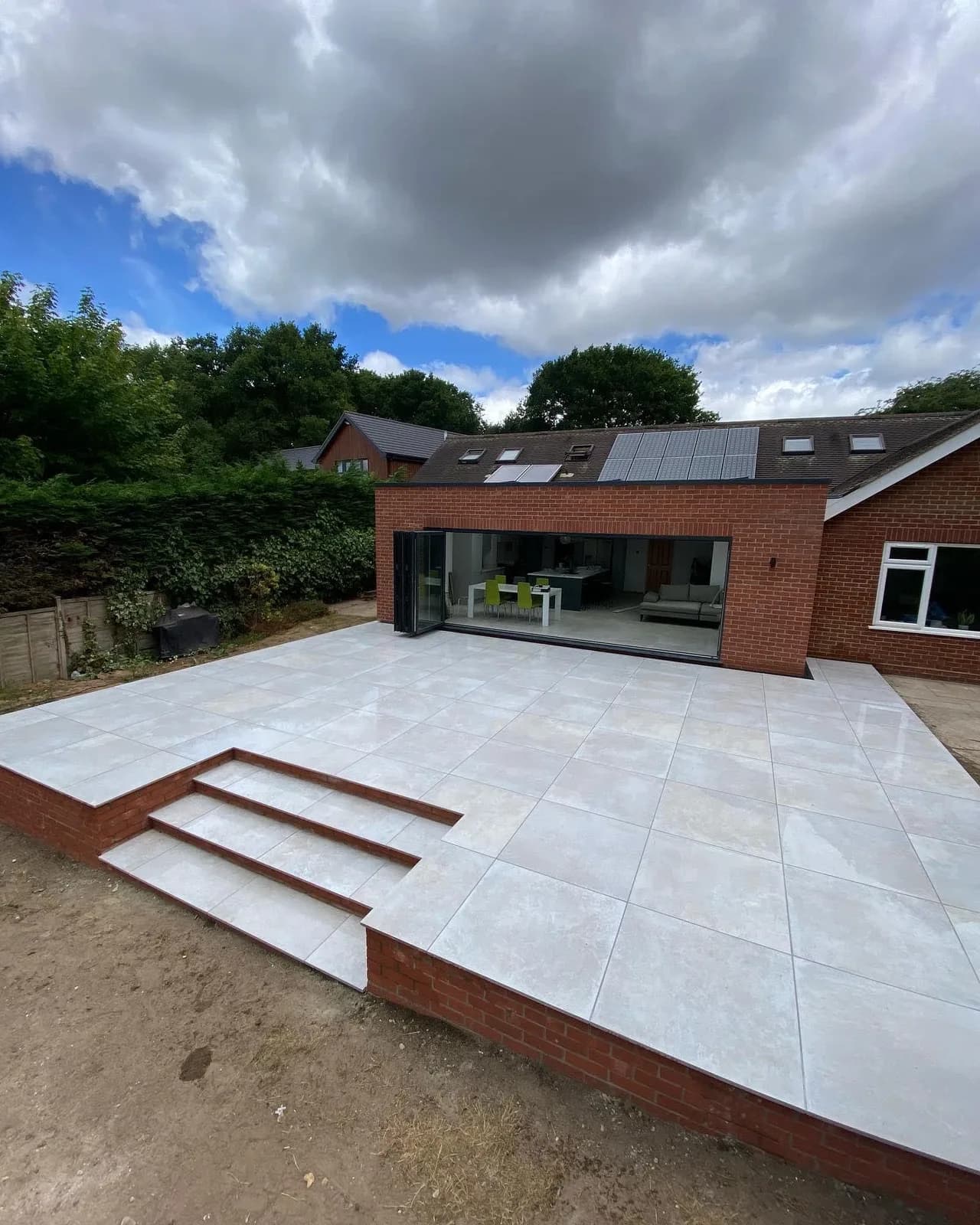 Large light-grey porcelain patio and steps outside a modern brick extension