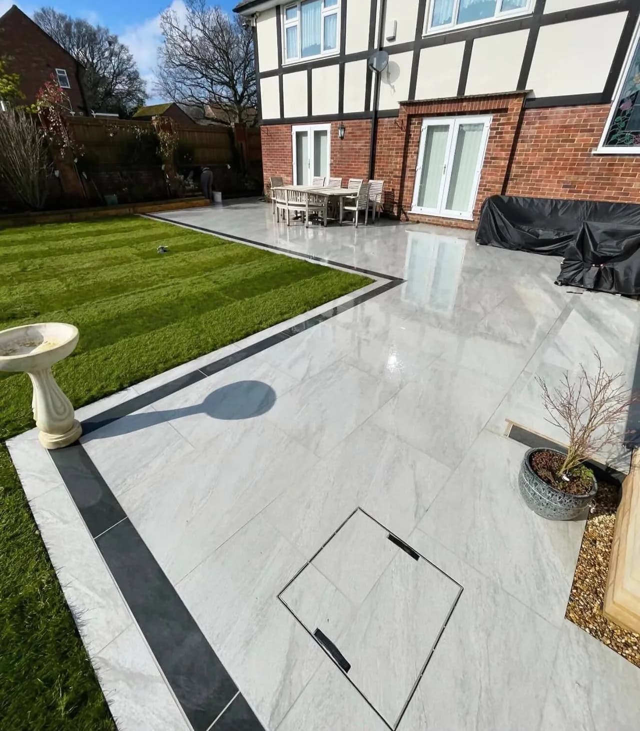 Landscaped garden with a light porcelain patio and contrasting dark border