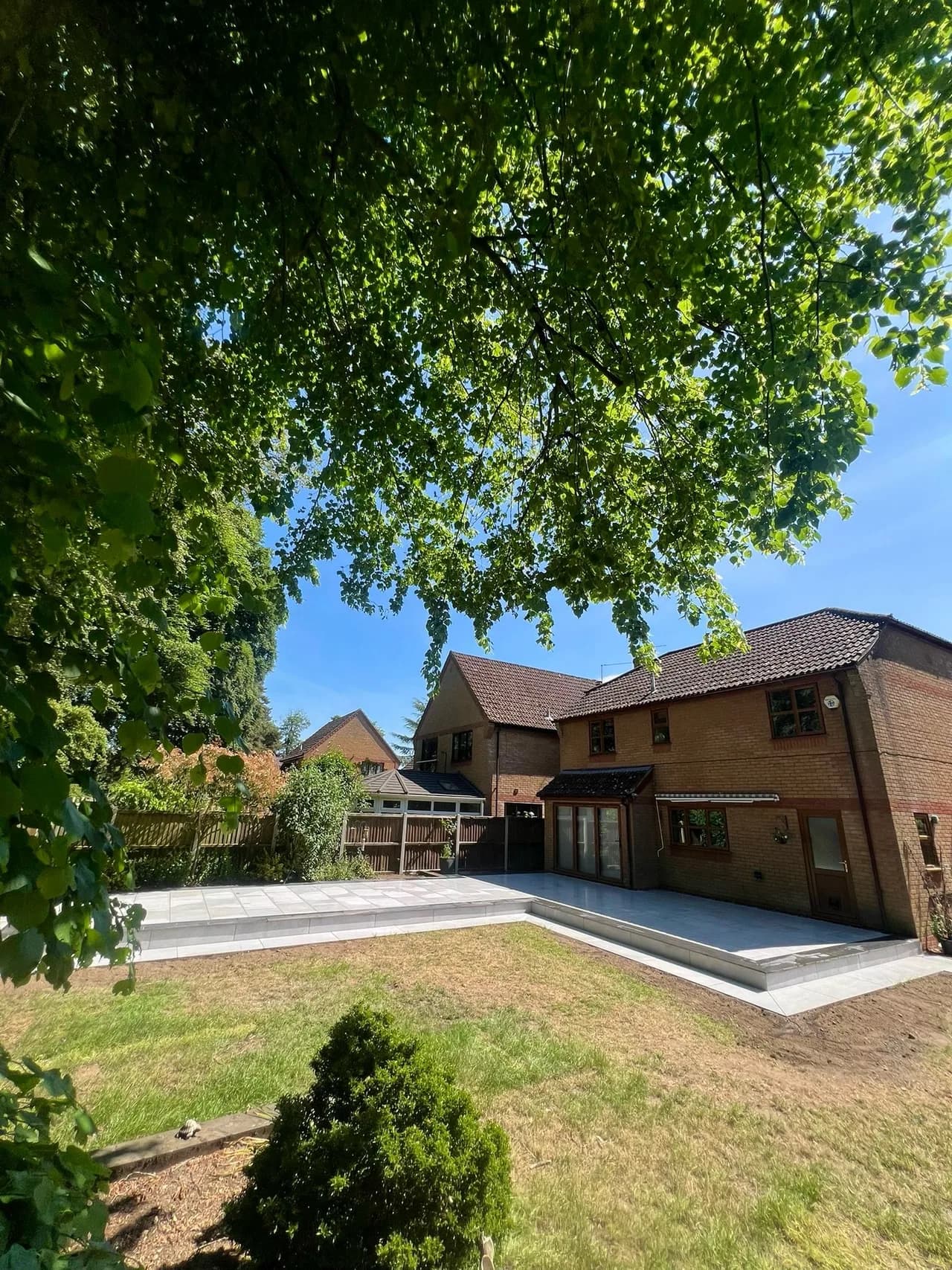 Wide porcelain patio surrounding a family home and garden