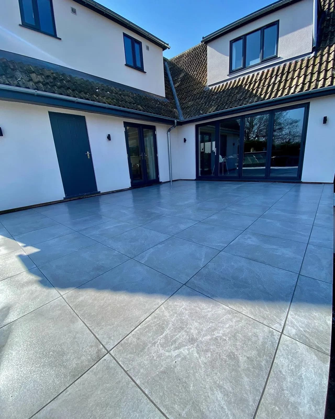 Modern dark-grey porcelain courtyard patio outside a renovated home