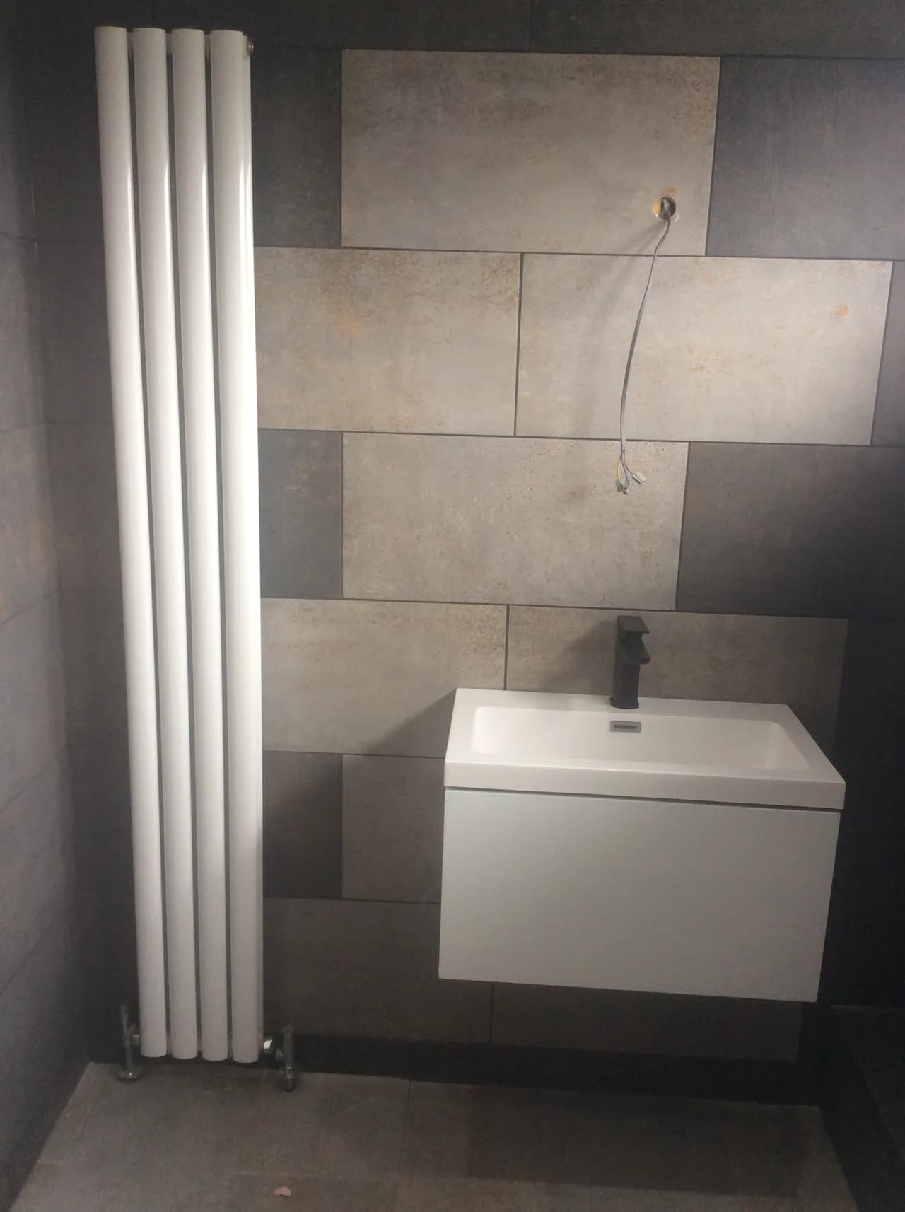 Installation of vertical radiator and wall hung drawer with sink and monobloc mixer tap.
